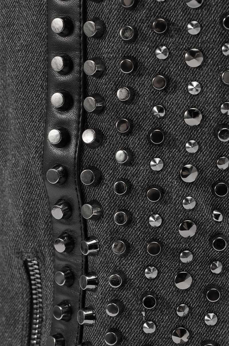 Close-up of the AZALEA WANG AGUSTUE BLACK STUDDED WESTERN BOOT, featuring dark gray fabric, rows of metallic studs, a black leather strip, and a partially visible zipper on the left.