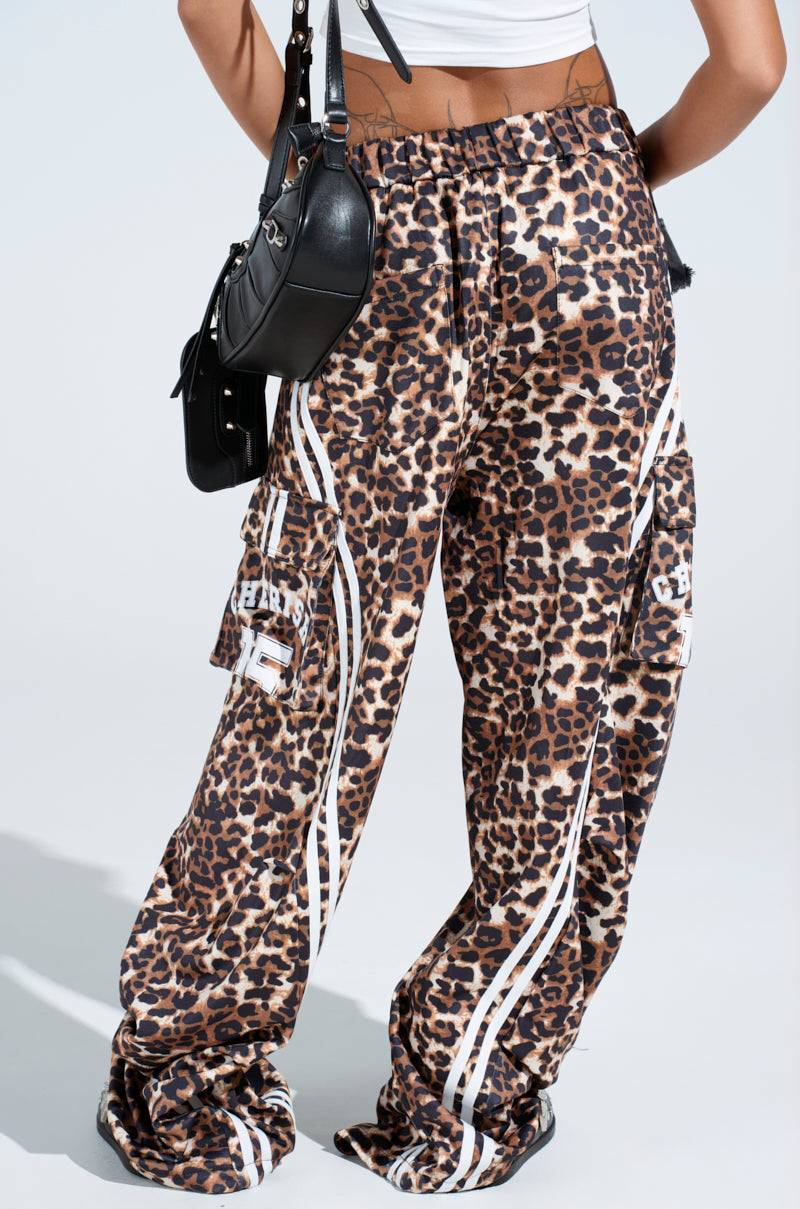 The individual is sporting the loose, high-rise CHERISH CHEETAH PANT with white side stripes, styled with a sleek black handbag and a crisp white top for a relaxed yet trendy look.