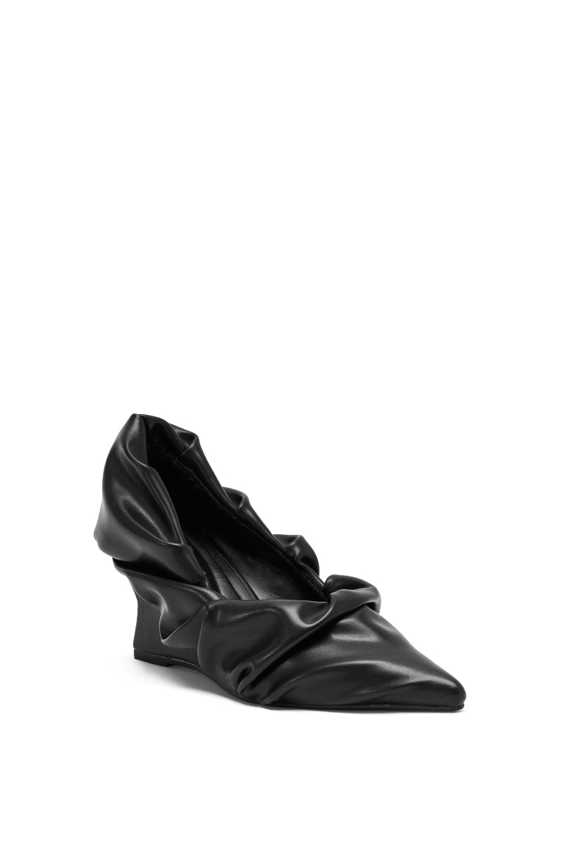 The AZALEA WANG AICHA BLACK RUCHED WEDGE PUMP is a faux leather shoe with a pointed toe and low sculptural heel, featuring ruched detail, shown here in black against a white background.