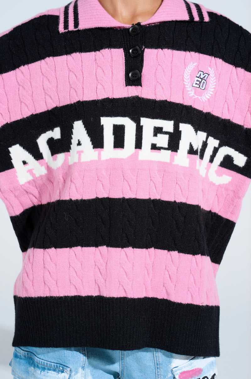 Wearing the ACADEMIC STRIPE SWEATER with “ACADEMIC” in white letters and an embroidered crest on soft cable knit, styled with light blue denim bottoms.