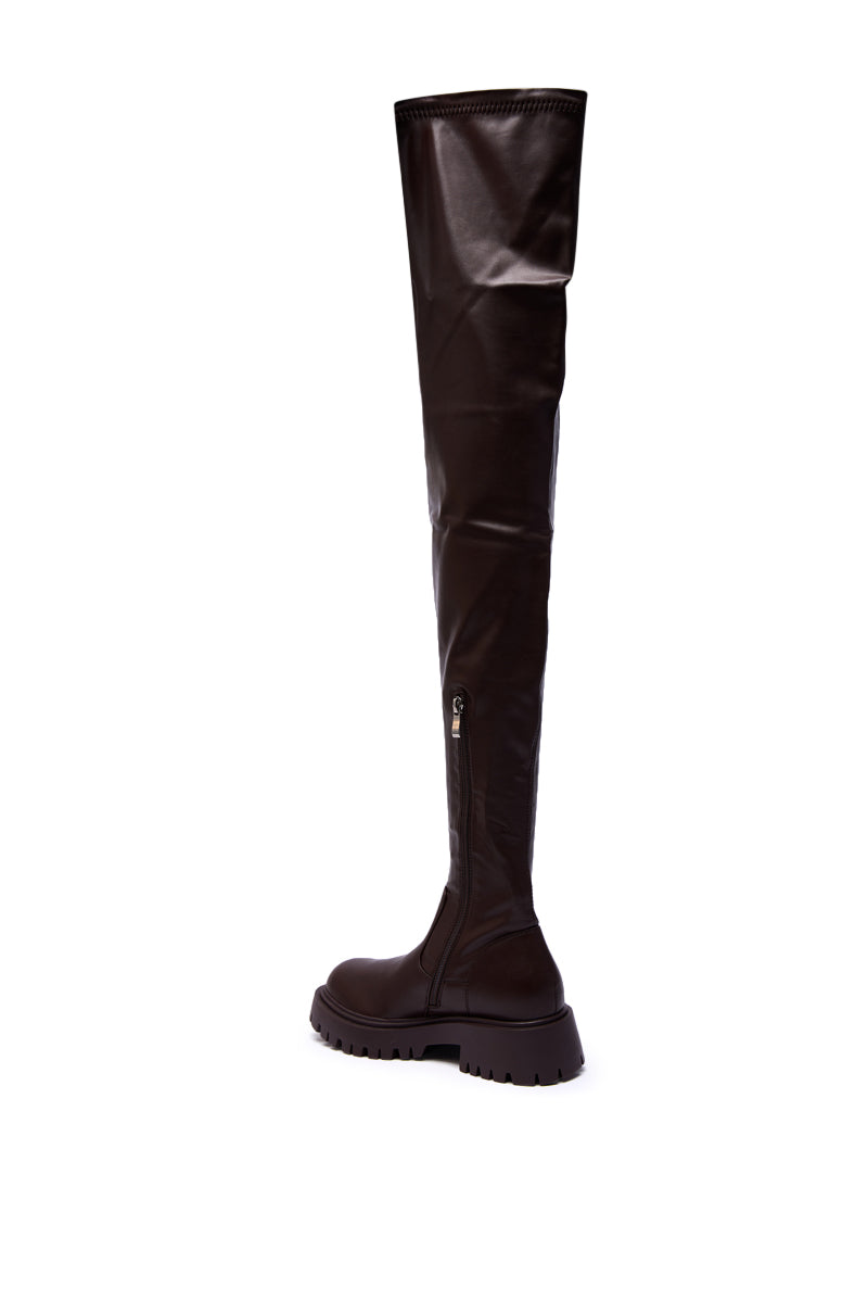 The AZALEA WANG AJUNA Chocolate Four Way Stretch PU Flat Boot is a single thigh-high brown faux leather boot with a chunky sole and side zipper, shown against a white background, facing left.