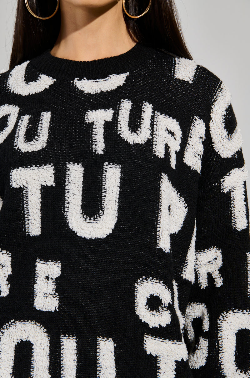 A woman is seen wearing a stylish FOREVER COUTURE LONG SLEEVE KNIT SWEATER, featuring bold white letters in different orientations on a black background. Her long, straight hair cascades down as she accessorizes with large hoop earrings, drawing attention to the sweater's upper portion and her flowing hair. 6