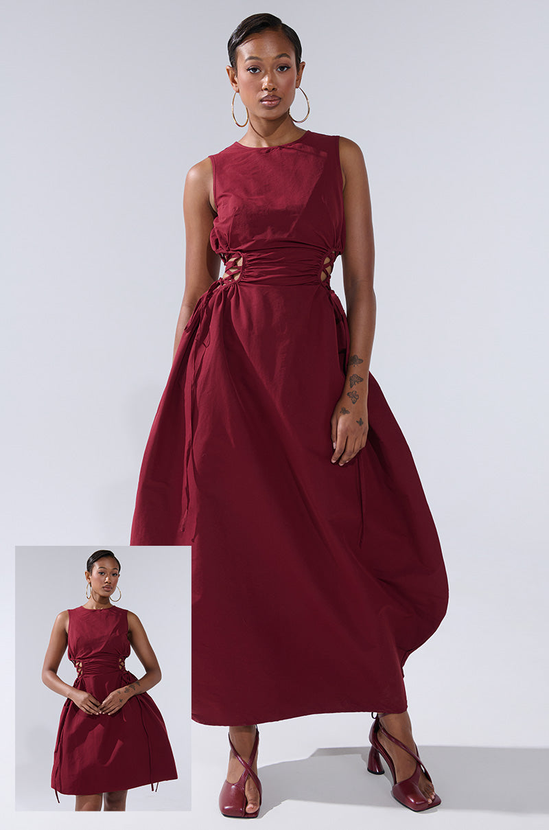A woman wears the ALINA LACE UP DETAIL MAXI DRESS IN BURGUNDY, a sleeveless maxi dress with side ties, paired with hoop earrings and red shoes. An inset highlights its adjustable gathered fit as she holds the sides.
