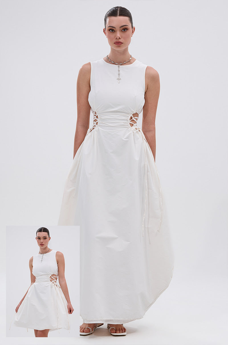 A woman models the ALINA Lace Up Detail Maxi Dress in White, a sleeveless cotton-blend style featuring a lace-up waist and asymmetric hem. An inset shows her lifting the skirt to reveal more of the lace-up detailing.
