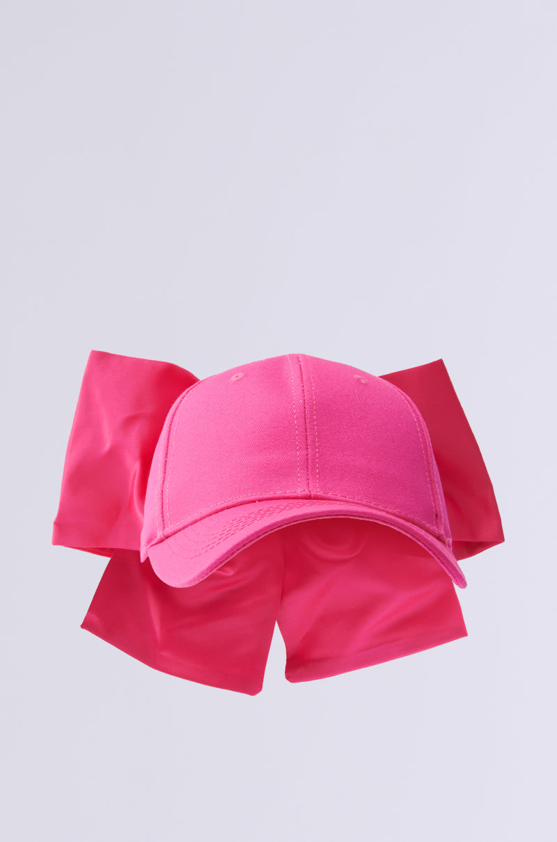 A vibrant pink VALENTINA BOW HAT boasts a large, oversized bow on the back, contrasting with a simple light gray background.