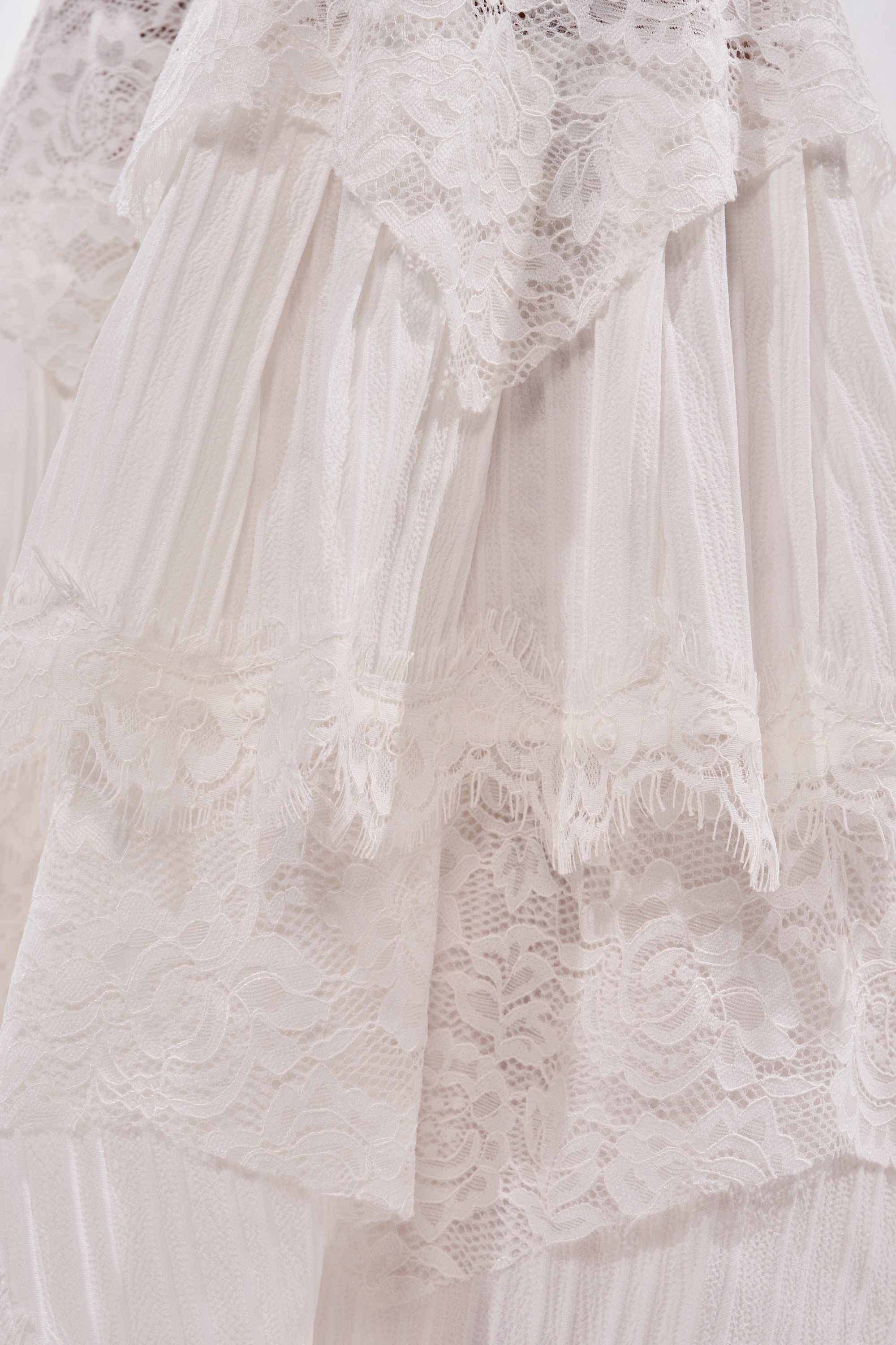 Close-up of layered white lace on the COACHELLA LACE RUFFLE PANTS, featuring intricate floral patterns and scalloped edges for a delicate, elegant texture. 10