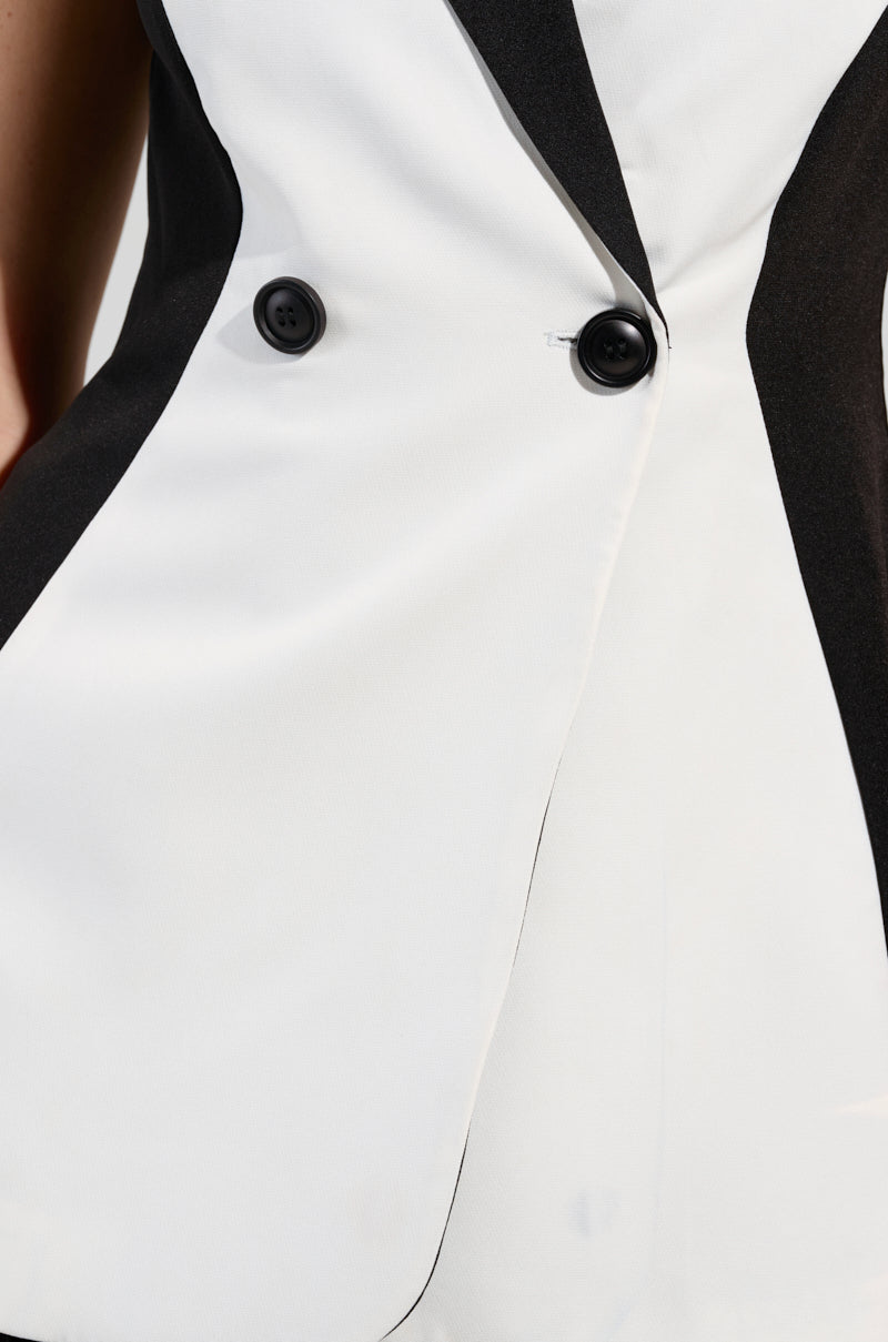 Close-up of the LABOR OF LOVE COLOR BLOCK BLAZER VEST, showcasing a black and white color block pattern with an asymmetrical design. This structured piece features two large black buttons and a sleek, modern cut. The fabric appears smooth and well-tailored, emphasizing the contrast between the black and white sections.