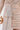 Close-up of a woman wearing the FELT CUTE RUCHED MINI DRESS in shimmering gold metallic stretch-knit, featuring a draped waist detail, holding a round gold clutch. Only her body from chest to mid-thigh is shown.