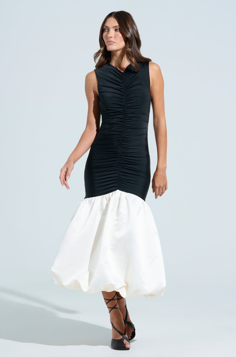 A woman poses against a light background in the WITH THE TRENDS BUBBLE MIDI DRESS, showcasing its black ruched bodice and voluminous white hem. She pairs it perfectly with black strappy heels, her hair styled in loose waves.