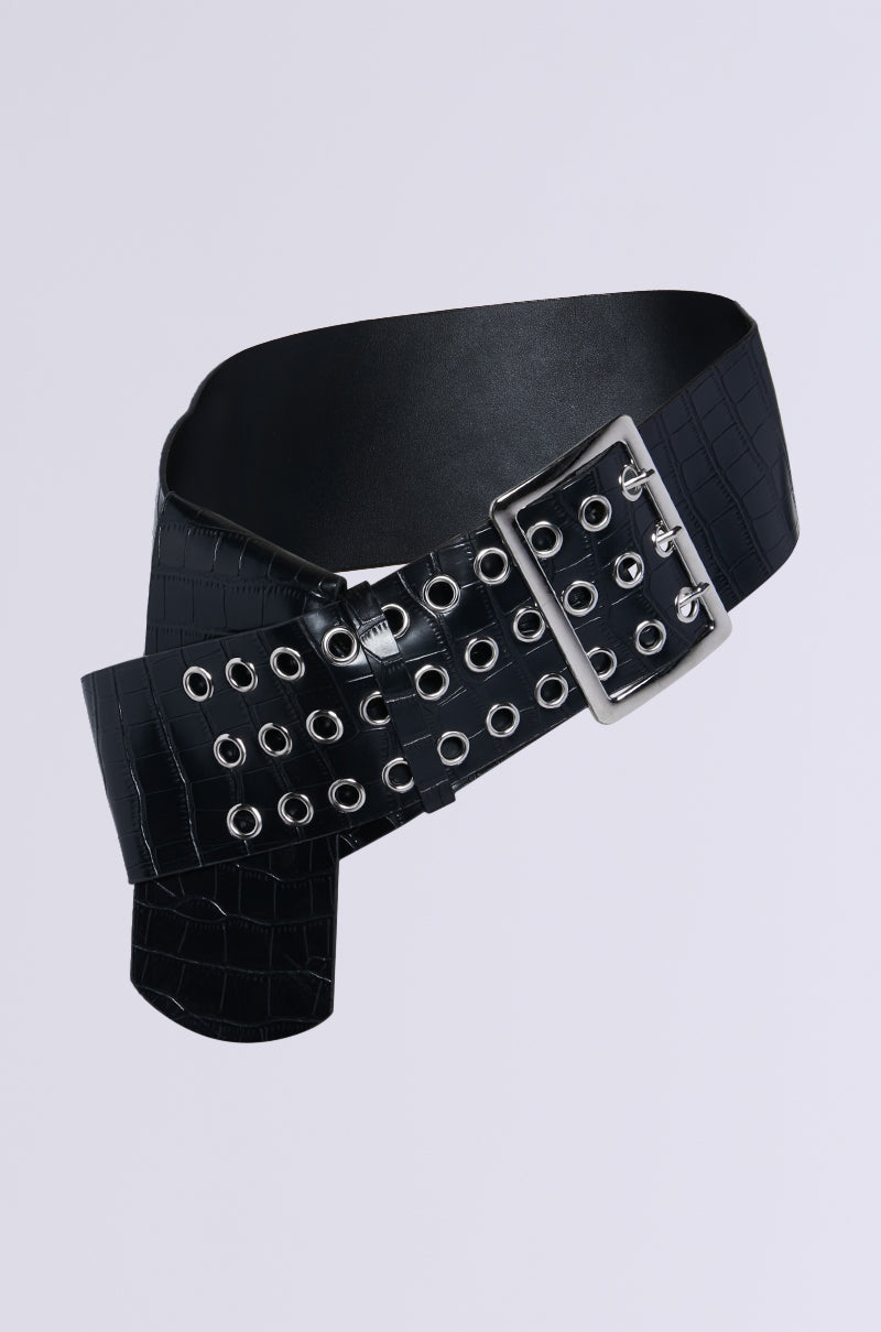 The ON TREND OVERSIZED LOW RISE BELT, a black faux leather accessory with crocodile texture and snakeskin pattern, showcases multiple silver grommets and a large rectangular buckle against a plain background.