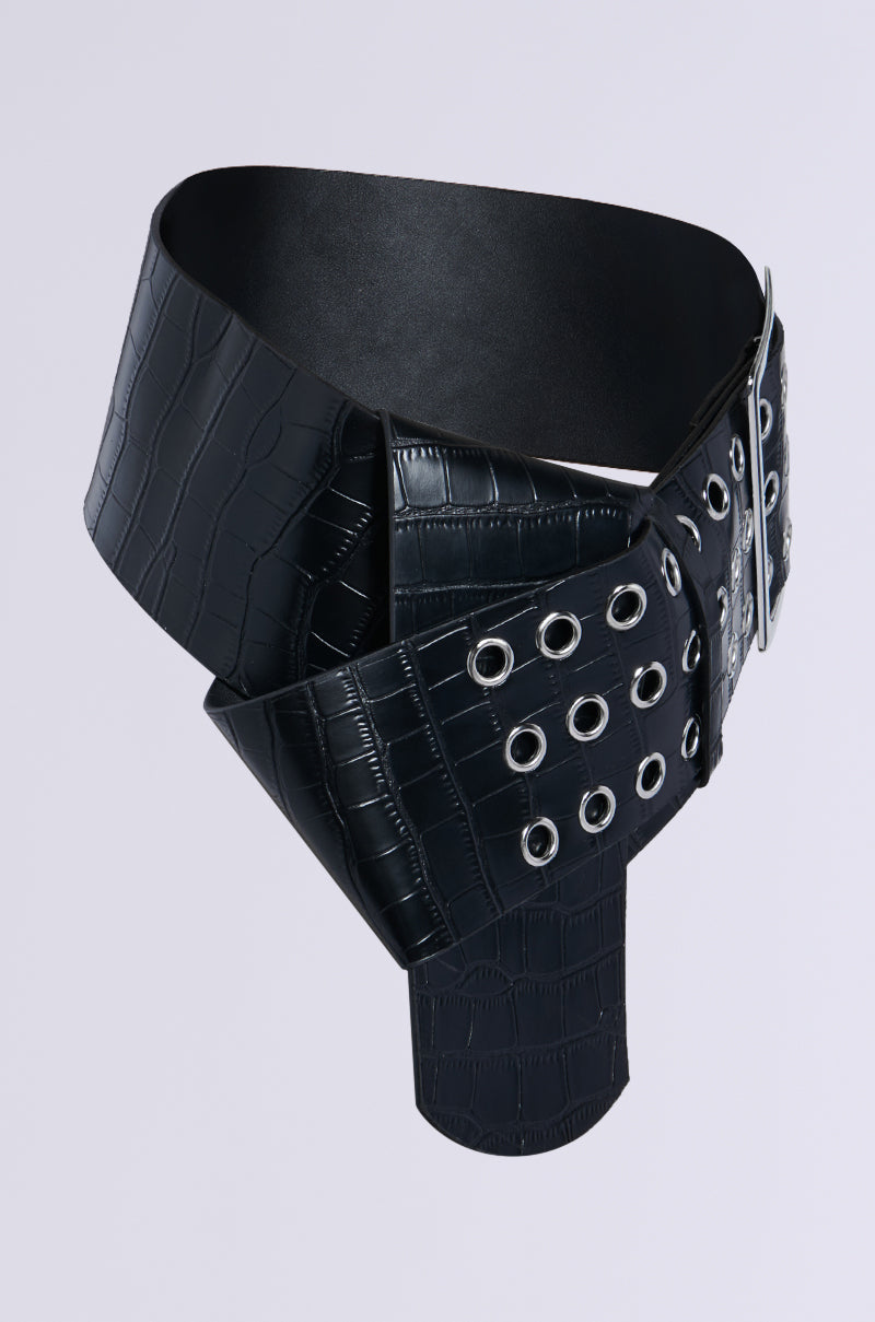 The ON TREND OVERSIZED LOW RISE BELT features a wide black faux leather with a crocodile texture and multiple silver grommets in rows, styled in an overlapping design with a metallic buckle for an edgy look.