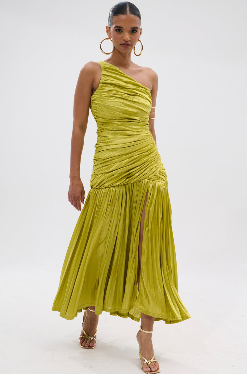A woman confidently poses against a plain white background in the LIFE OF THE PARTY SATIN MIDI DRESS, a one-shoulder lime-green ruched satin midi with a pleated skirt and thigh-high slit, styled with gold hoop earrings and strappy gold heels.