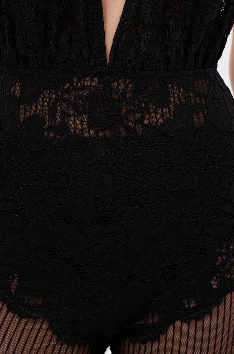 Close-up of the KEEP ON WALKIN MESH JUMPSUIT featuring a black lace bodice with deep V neckline, sheer floral details, and paired with black fishnet stockings.