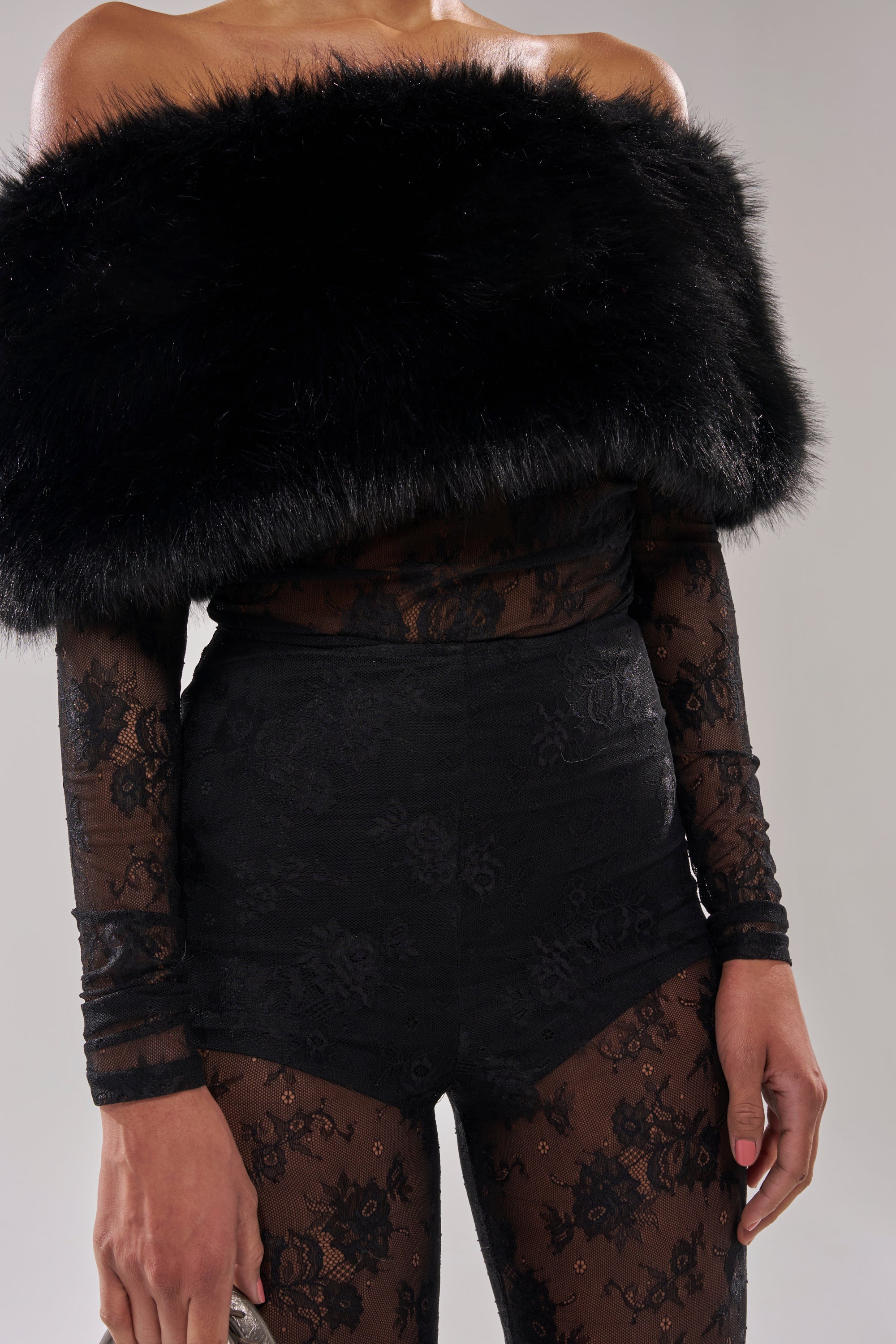 Wearing the DELARA FUR TRIM LACE JUMPSUIT, featuring a faux fur collar and sheer black lace layered over high-waisted shorts, creates an elegant and fashion-forward look.