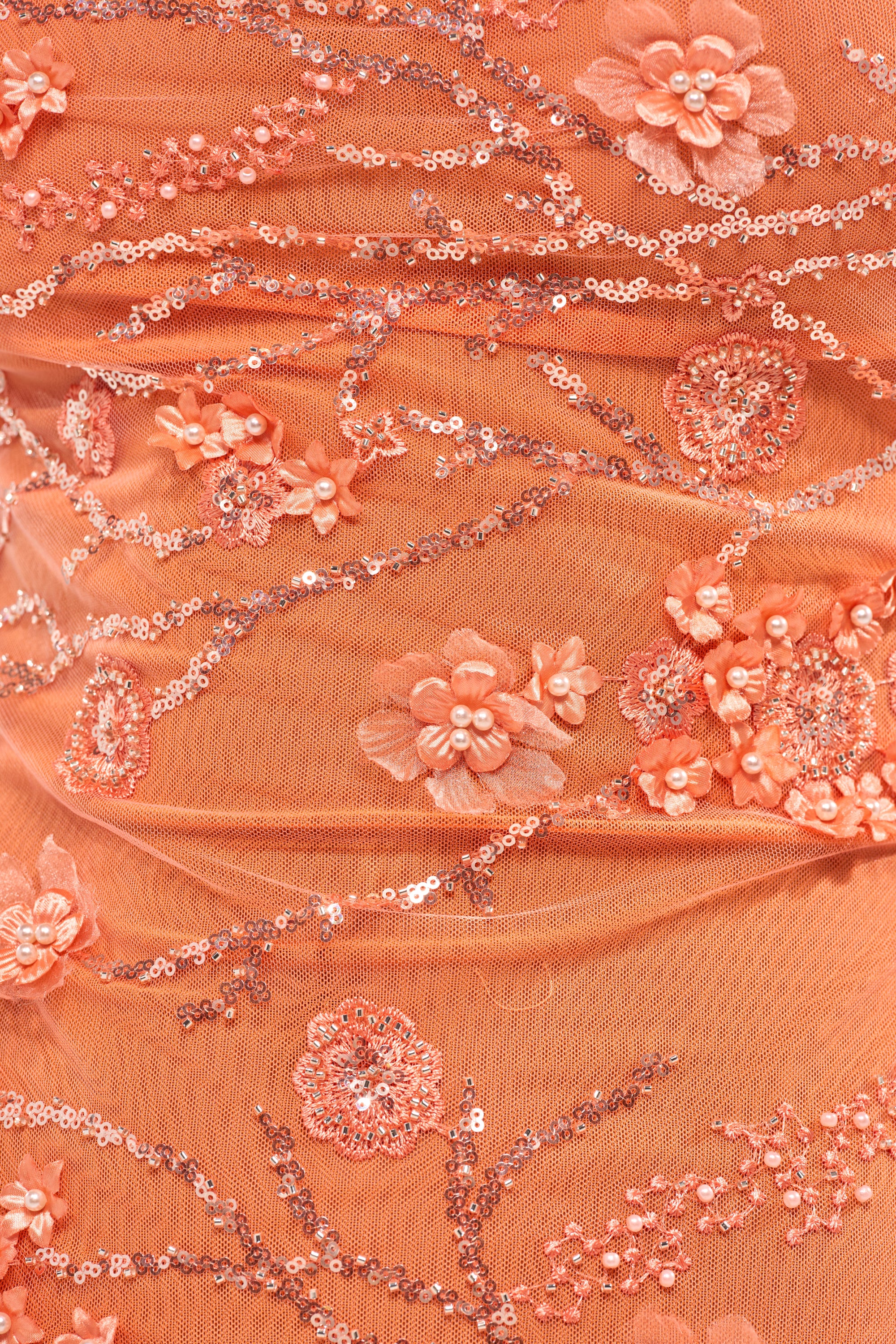 Close-up of the SWEET LIKE ME MINI DRESS IN ORANGE, a mini dress featuring intricate peach-toned fabric with embroidered flowers, sequins, and beads for a detailed, textured floral pattern. 10