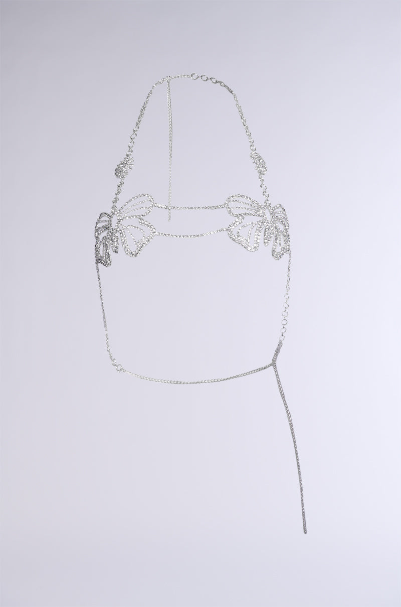 Introducing the WATCH ME FLY BODY CHAIN: a delicate silver body chain adorned with intricate butterfly designs on the bust area. This harness features an adjustable neck chain and a long, dangling chain on one side, creating an elegant and artistic Y2K accessory. The background is set against a plain light grey backdrop.