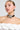 A person with slicked-back hair pairs a COUTURE FLOWER CHOKER NECKLACE featuring a hammered rose pendant with large silver earrings and a white textured off-shoulder top. The neutral background highlights both the jewelry and the outfit.