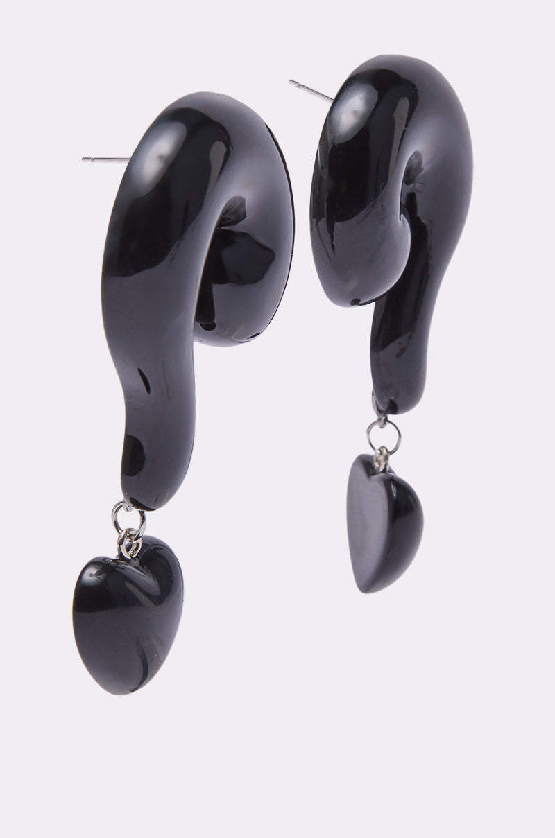 The NO QUESTIONS EARRING is a pair of glossy black acrylic earrings shaped like question marks, each with a small black heart-shaped pendant dangling from the curved end. 2