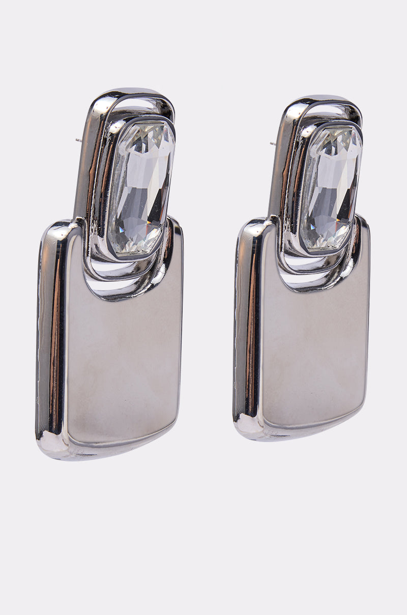 MOD EARRING: Modern geometric earrings featuring rectangular silver bases and large, clear faceted gemstones set at the top, photographed on a plain white background. 2
