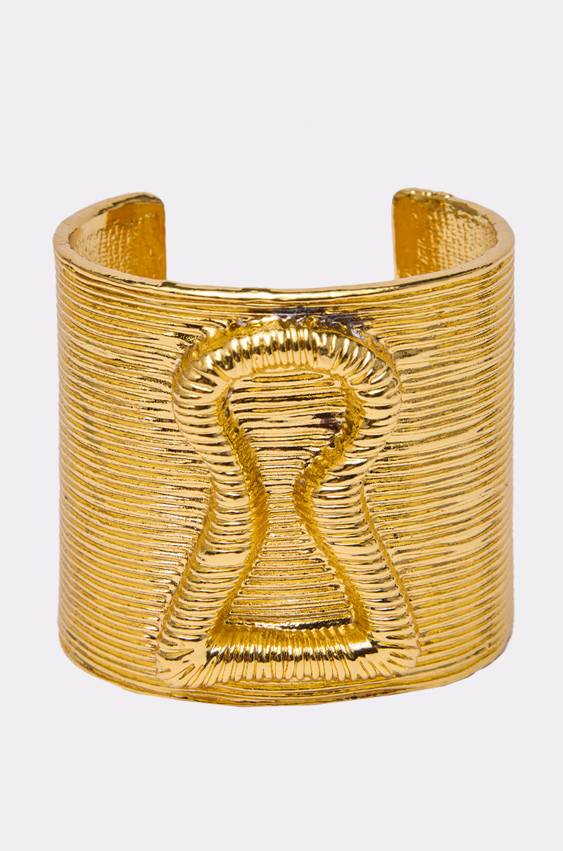 The IM THE KEY BRACELET is a bold, textured gold cuff featuring a raised keyhole design on the front, making this unique keylock jewelry piece stand out against a plain white background.