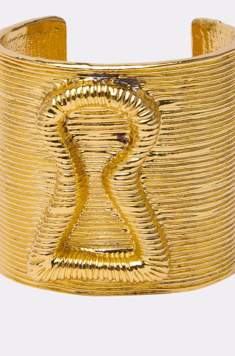 The IM THE KEY BRACELET from AKIRA Label is a wide, textured gold slip-on cuff featuring a raised keyhole-shaped center design. 7