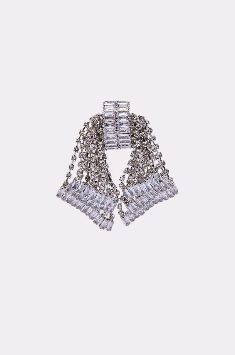 The ELI EARRING, featuring a silver bow shape adorned with rows of clear rectangular and round rhinestones, pairs beautifully with statement pieces and stands out against a plain white background.
