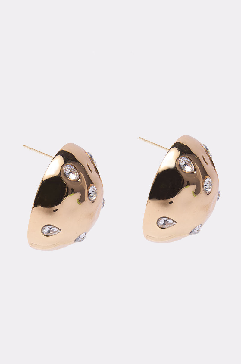 The PARI EARRING is a gold metallic pair with a polished finish, clear teardrop crystals, and subtle rhinestone accents, shown against a plain light background.