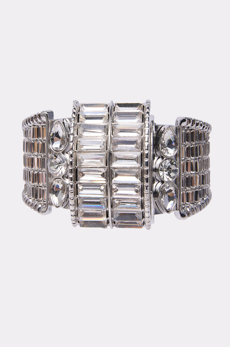 The DIAMONDS DANCING BRACELET features a wide band adorned with rectangular, teardrop, and baguette-cut clear gemstones set in symmetrical rows for a bold, elegant look.