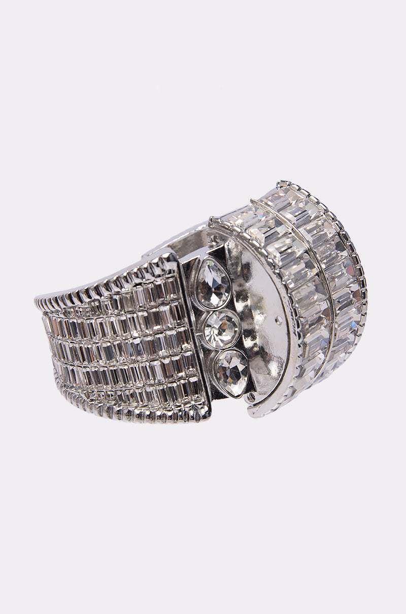 A close-up of the DIAMONDS DANCING BRACELET, a silver-toned wide-band piece adorned with rectangular and round clear gemstones, including baguette-cut rhinestones, arranged in geometric patterns and displayed on a white background.
