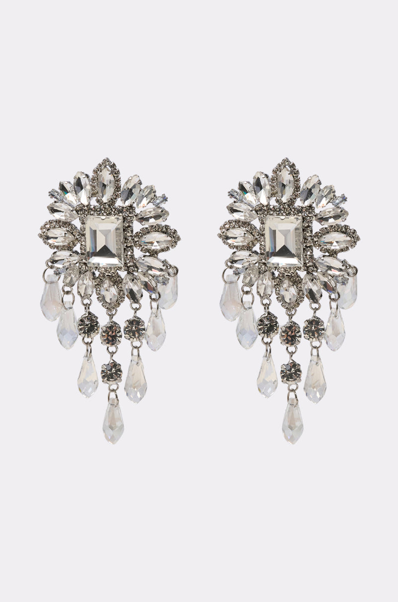 THE MAIN MOMENT EARRING: Ornate chandelier earrings adorned with clear rhinestones in various shapes, featuring a large central square stone, surrounded by smaller stones and dangling teardrop crystals.