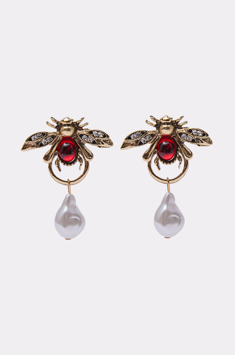 The OLD MONEY EARRING features vintage-inspired jeweled bees with red gemstone bodies, sparkling wings, and dangling irregular white pearl-like drops, shown against a white background. 0
