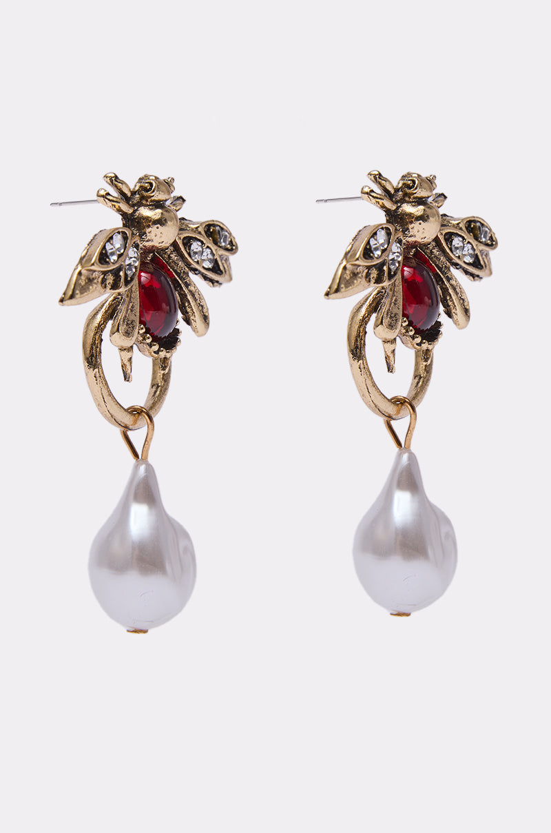 The OLD MONEY EARRING is a pair of bee-shaped earrings embellished with red and clear gemstones, finished with a dangling white teardrop pearl at the bottom. 2