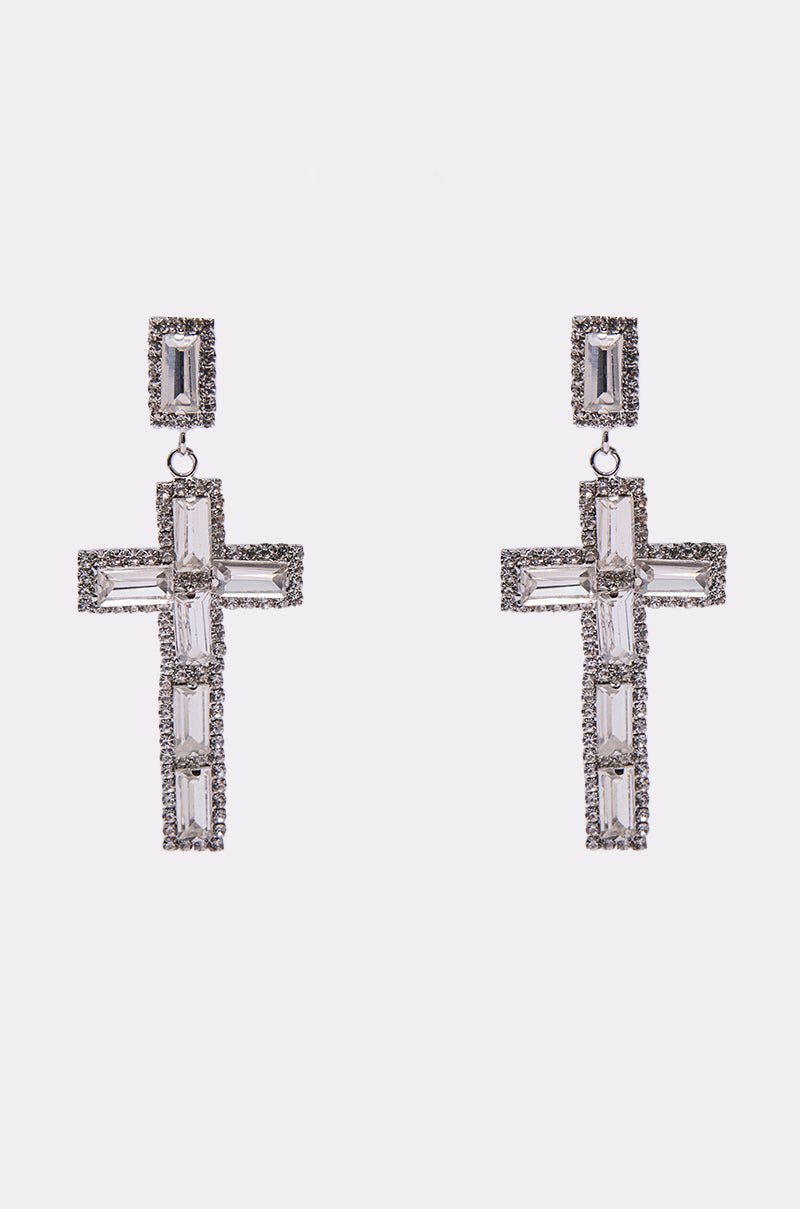 The RED CARPET EARRING is a pair of silver-tone dangling cross earrings adorned with rectangular and small round clear rhinestones, shown against a plain white background. 0