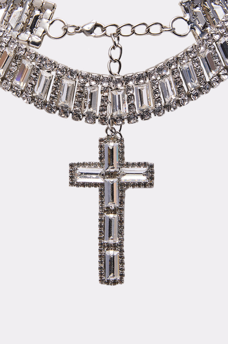 The CORY CROSS NECKLACE is adorned with rectangular clear gemstones and a large sparkling cross pendant, all shimmering beautifully at the center. 2