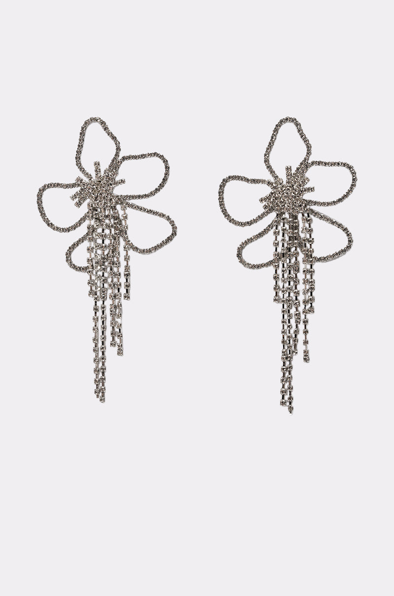 The CHECK MY DRIP EARRING features silver rhinestone bow shapes with flowing chain tassels, creating a striking fringe drop earring style, displayed on a plain white background.
