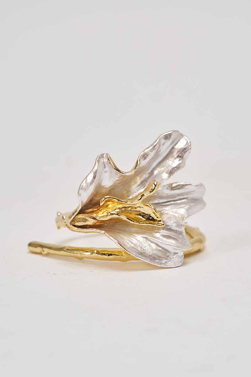 The TERRI BRACELET features a gold and silver design inspired by delicate, blooming flowers with textured petals and a curved silhouette, showcasing mixed-metal elegance against a plain white background. 1