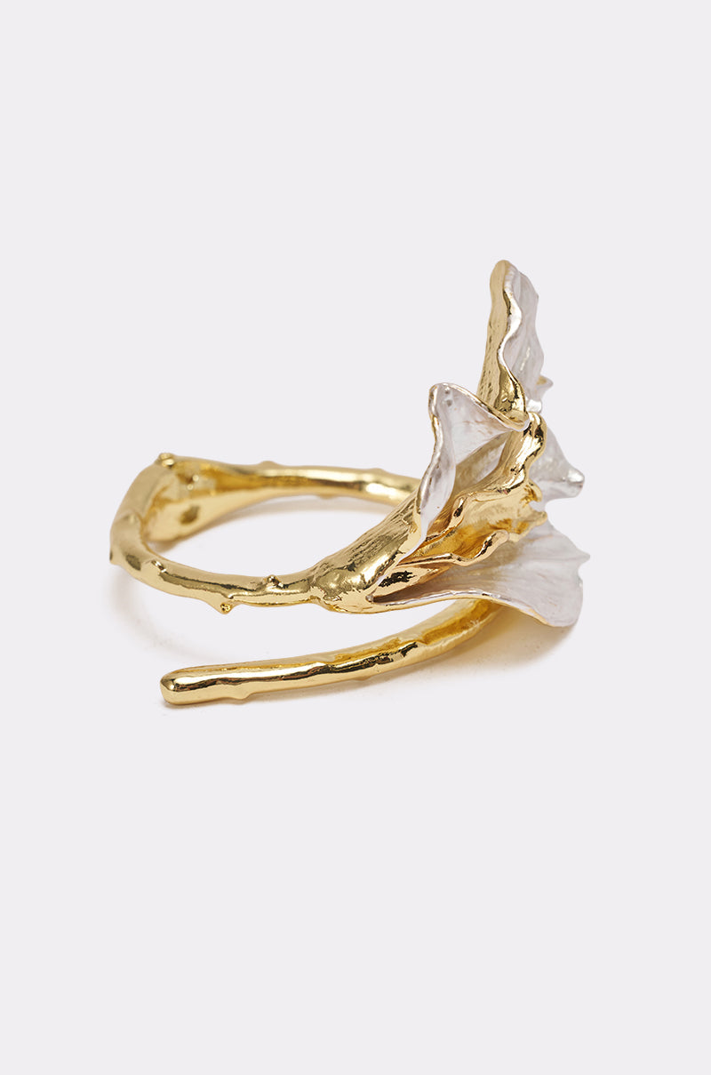 The TERRI BRACELET is a mixed-metal floral cuff featuring a delicate, organic design with petal-like accents, reminiscent of flowers or seashells. 2