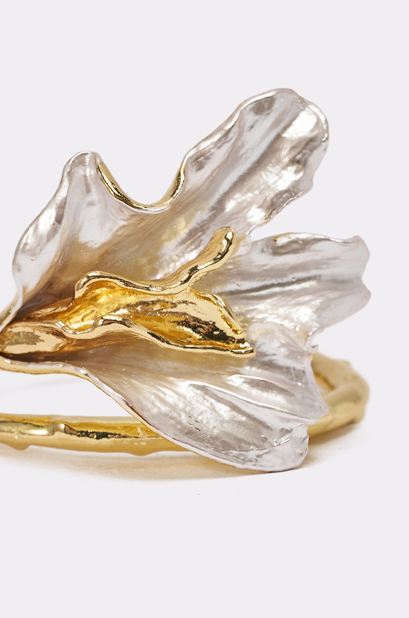 The TERRI BRACELET features a delicate flower design with translucent, petal-like details in gold and silver tones, accented by lustrous pearls on a light gray background. 4