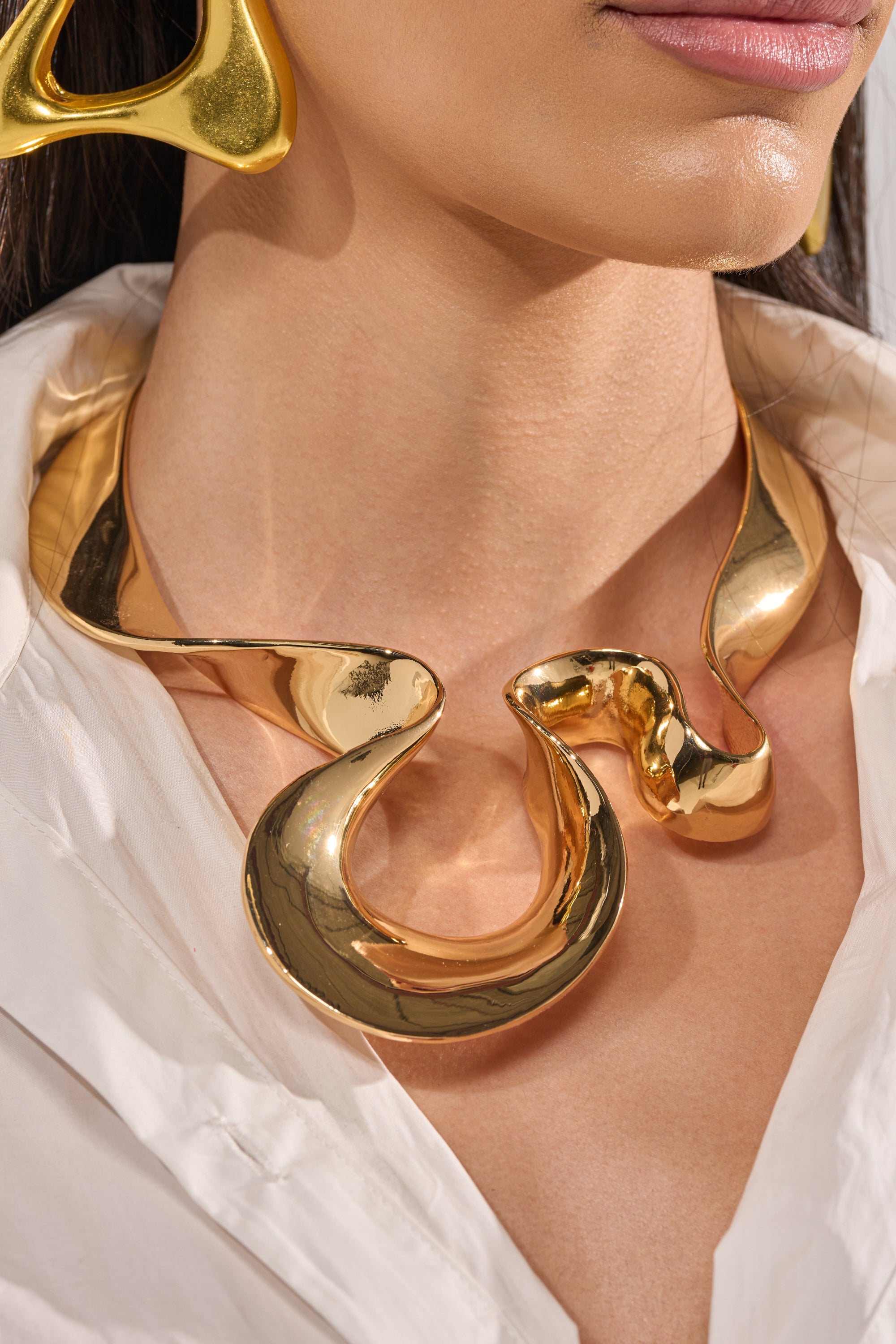 A woman wearing the PURE VIBES NECKLACE, a high-polish finish gold collar necklace. 1