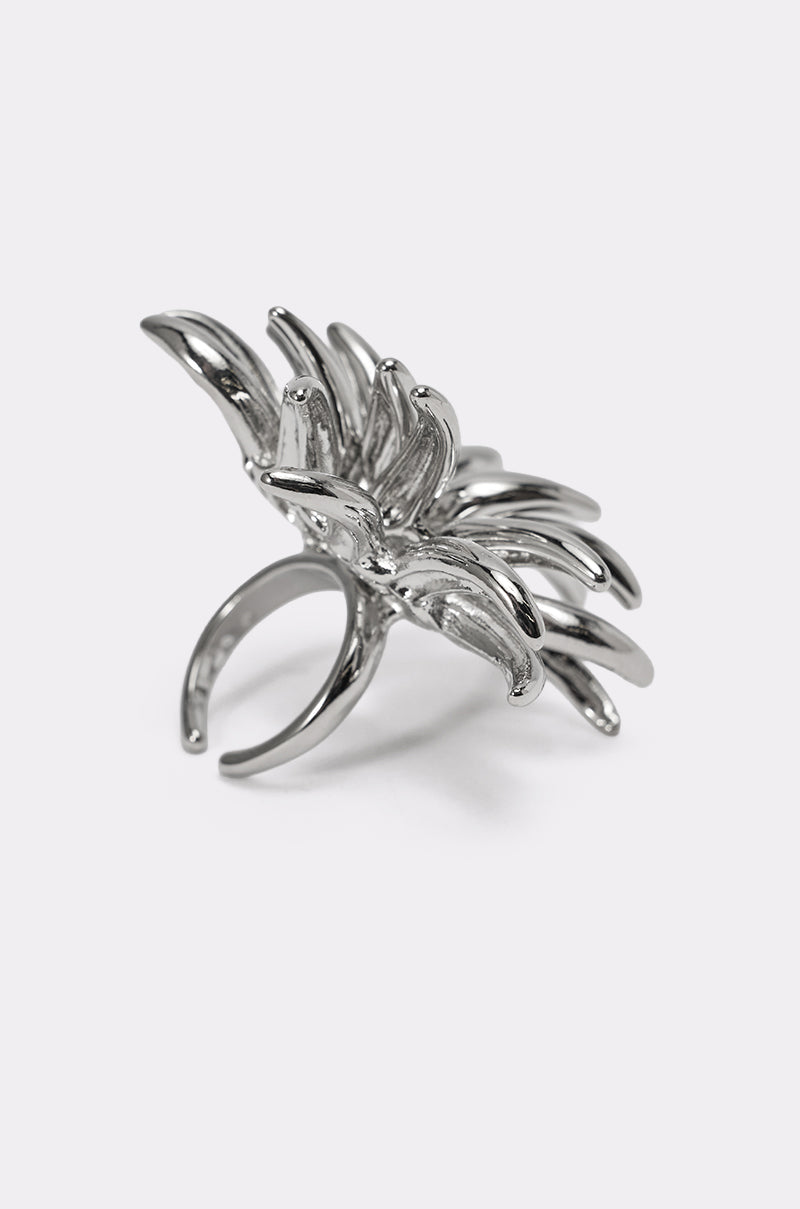 The JENNY SILVER RING features a spiked, abstract sculptural design with layered, curved petal-like shapes, displayed against a plain light background. 3