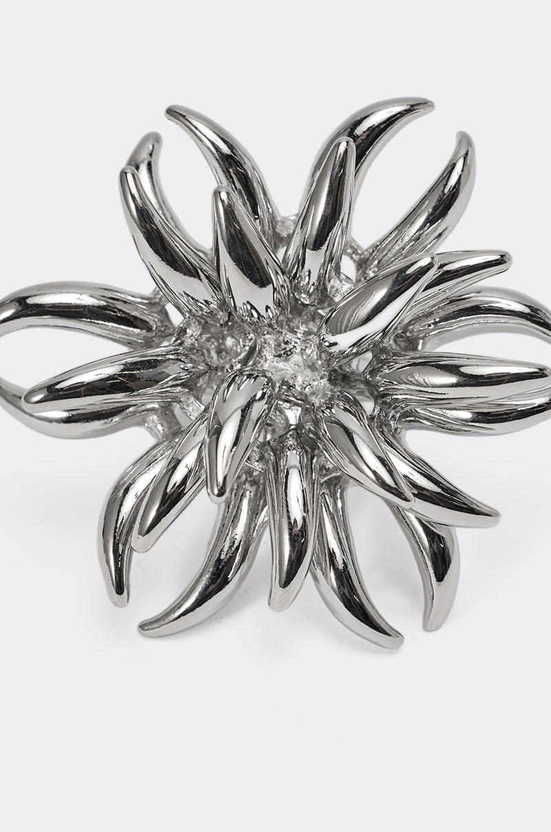 The JENNY SILVER RING is a shiny statement piece with a bold, abstract design featuring multiple curved, pointed silver spikes radiating outward like a stylized flower or sea urchin. 4