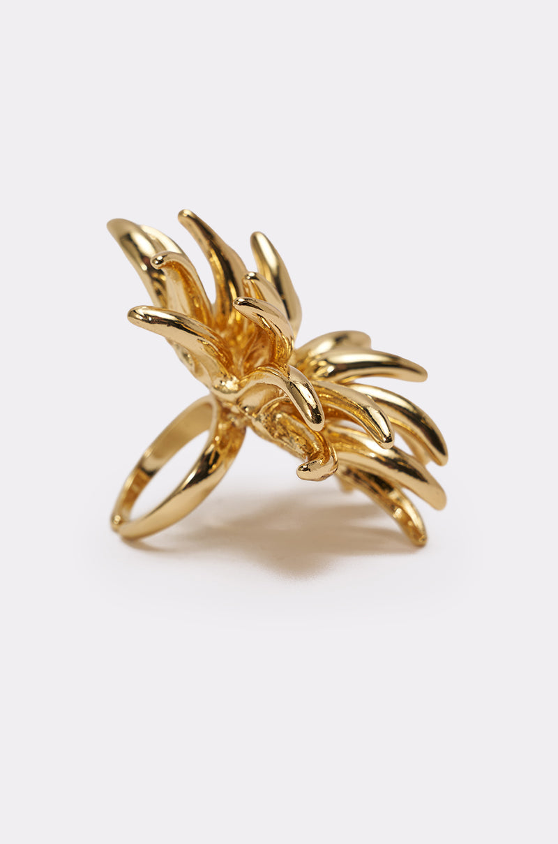 The SUNBURST GOLD RING is a statement piece with an abstract, sculptural design and bold gold spikes, showcased against a plain light background. 2