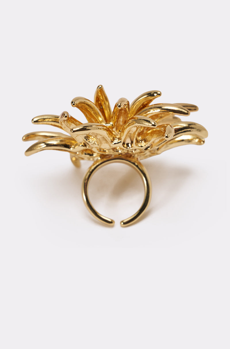 The SUNBURST GOLD RING is a gold spiked statement ring with an open band and a sculpted, layered flower design featuring curved petals that fan outward. 3