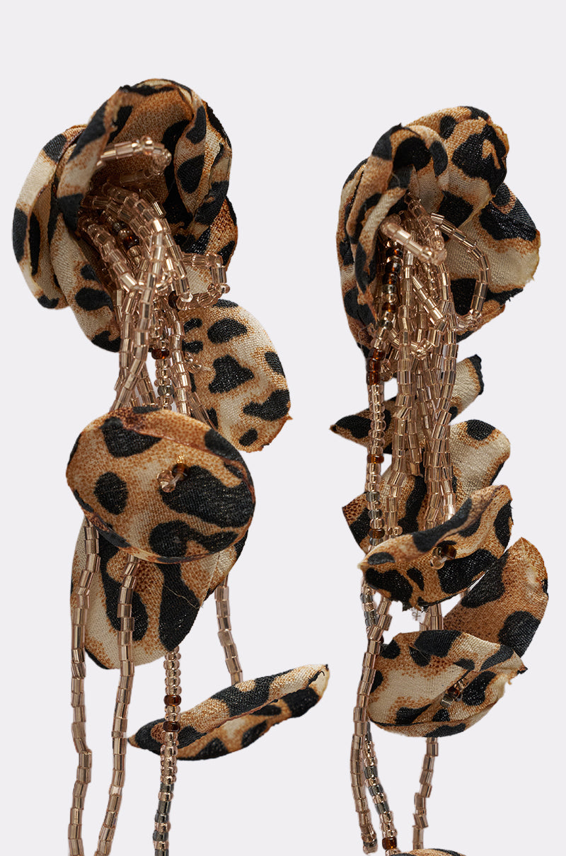Close-up of the LEAH EARRING, featuring fabric petals with a leopard print and golden beaded strands for bold, textured statement style. 3