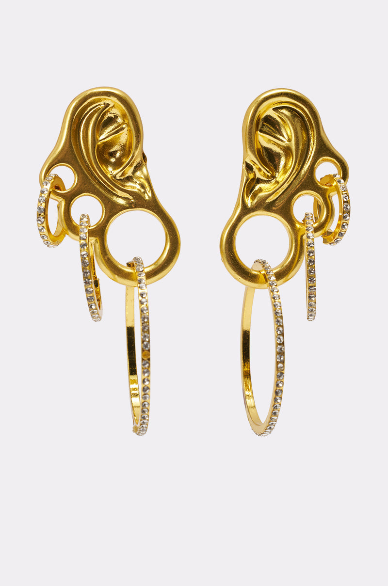 The IN MY EAR EARRING features gold ear-shaped studs, each adorned with three textured hoops including sparkling rhinestones, creating a unique and eye-catching artistic design. 0