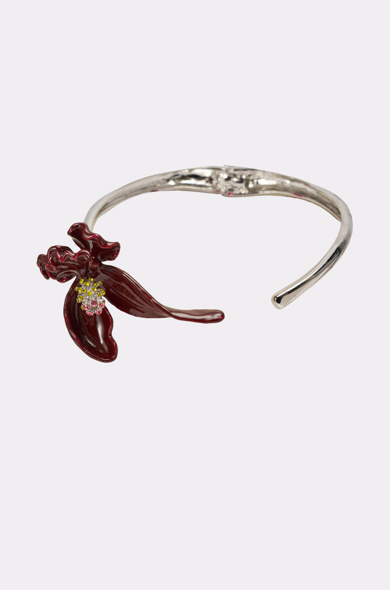 The FULL BLOOM NECKLACE features a detailed dark red enamel flower with green and yellow accents on a silver open cuff, perfect for lovers of statement floral designs. 2