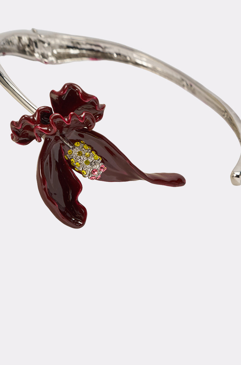 The FULL BLOOM NECKLACE features a bold silver design with a dark red, orchid-shaped enamel flower accented by yellow and pink jewels at its center, echoing statement elegance in a uniquely vibrant piece. 4