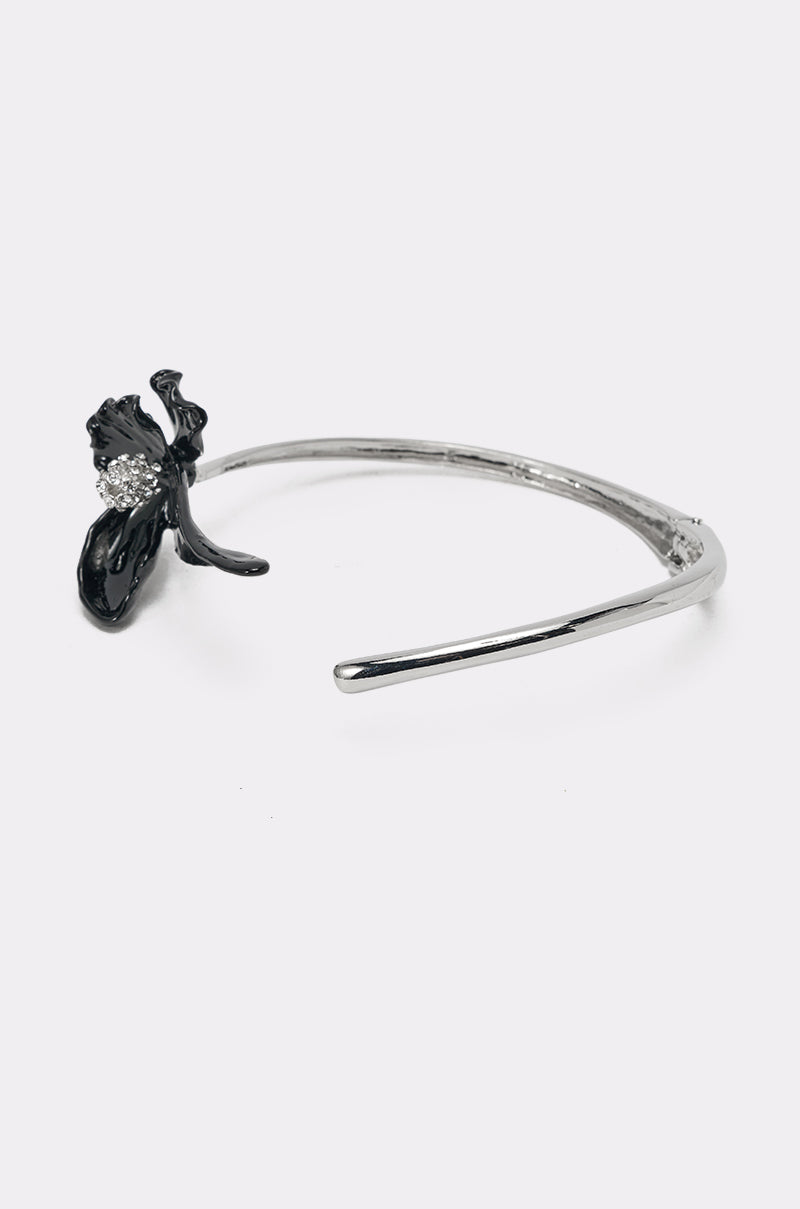 The FULL BLOOM NECKLACE is a silver-tone collar bracelet with a black flower centerpiece accented by sparkling rhinestones, displayed on a plain white background. 3
