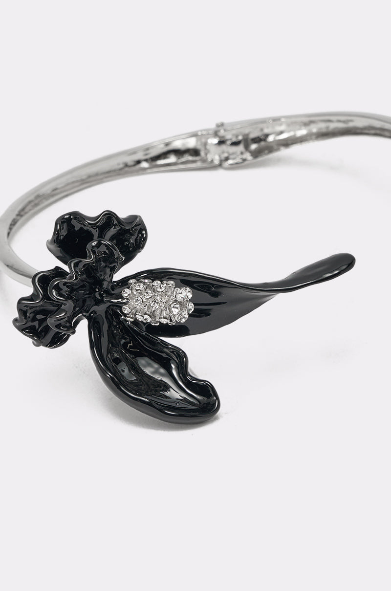 The FULL BLOOM NECKLACE is a silver-tone collar bracelet with a glossy black flower and sparkling clear stones at its center, shown on a white background. 4