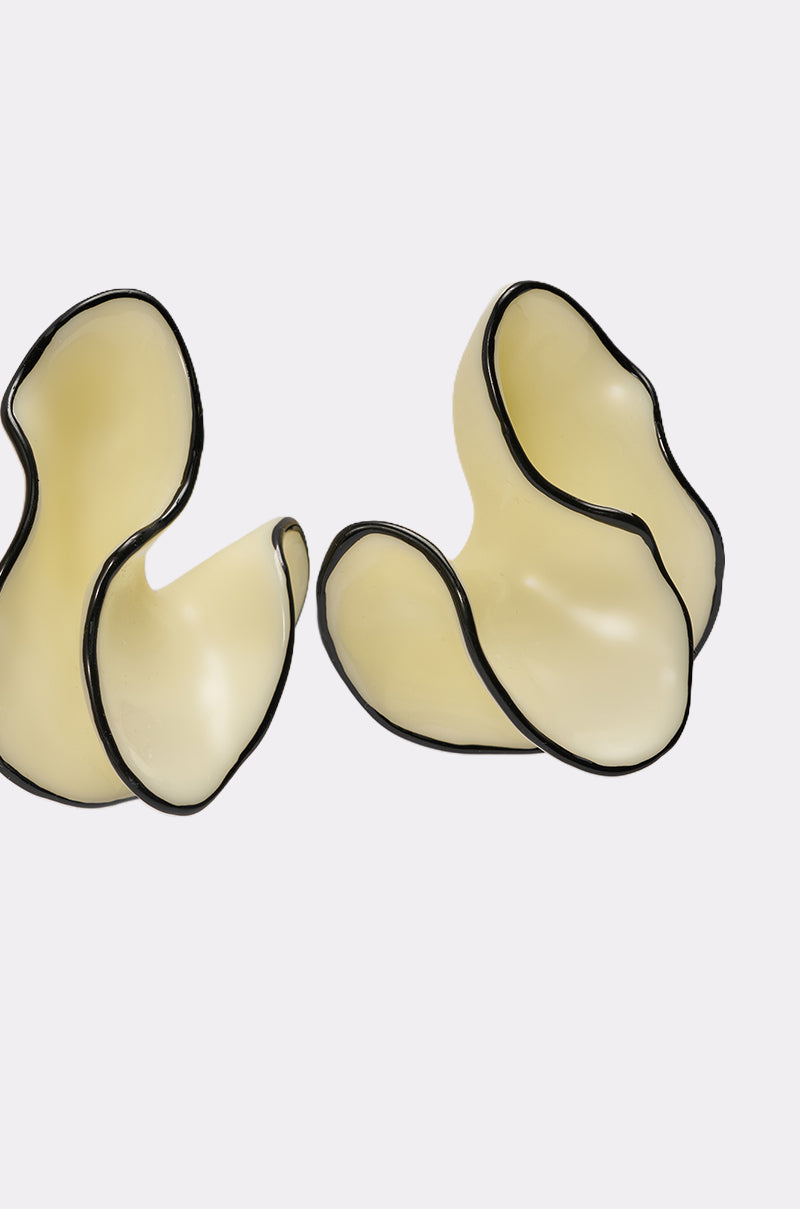 The ITS MY WORLD EARRING features abstract, cream glass with flowing, organic curves outlined in black, reminiscent of sculptural squiggle earrings, displayed on a plain white background. 3